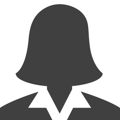 A man with dark hair and a light complexion, wearing a suit and smiling, is pictured against a plain black background.