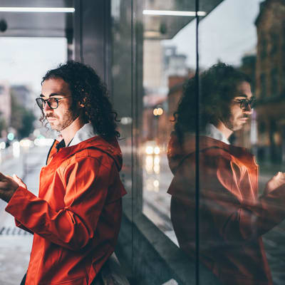 man looking at phone outside city
