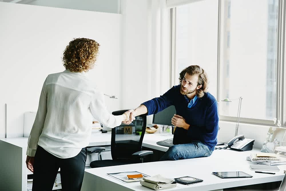 A man and a woman shaking hands in an office
