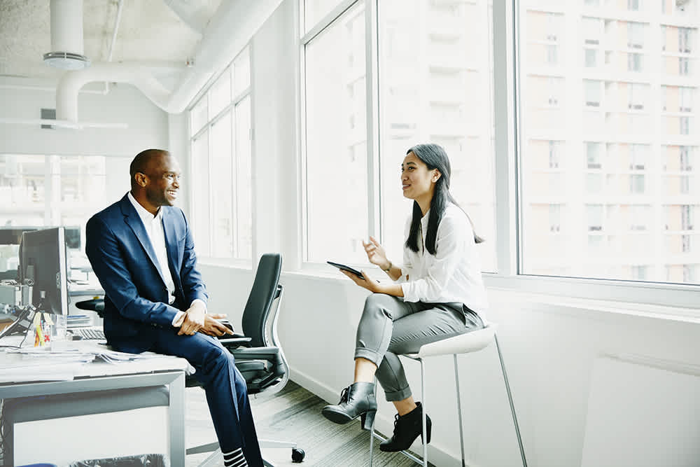 A man and a woman in an office having a conversation