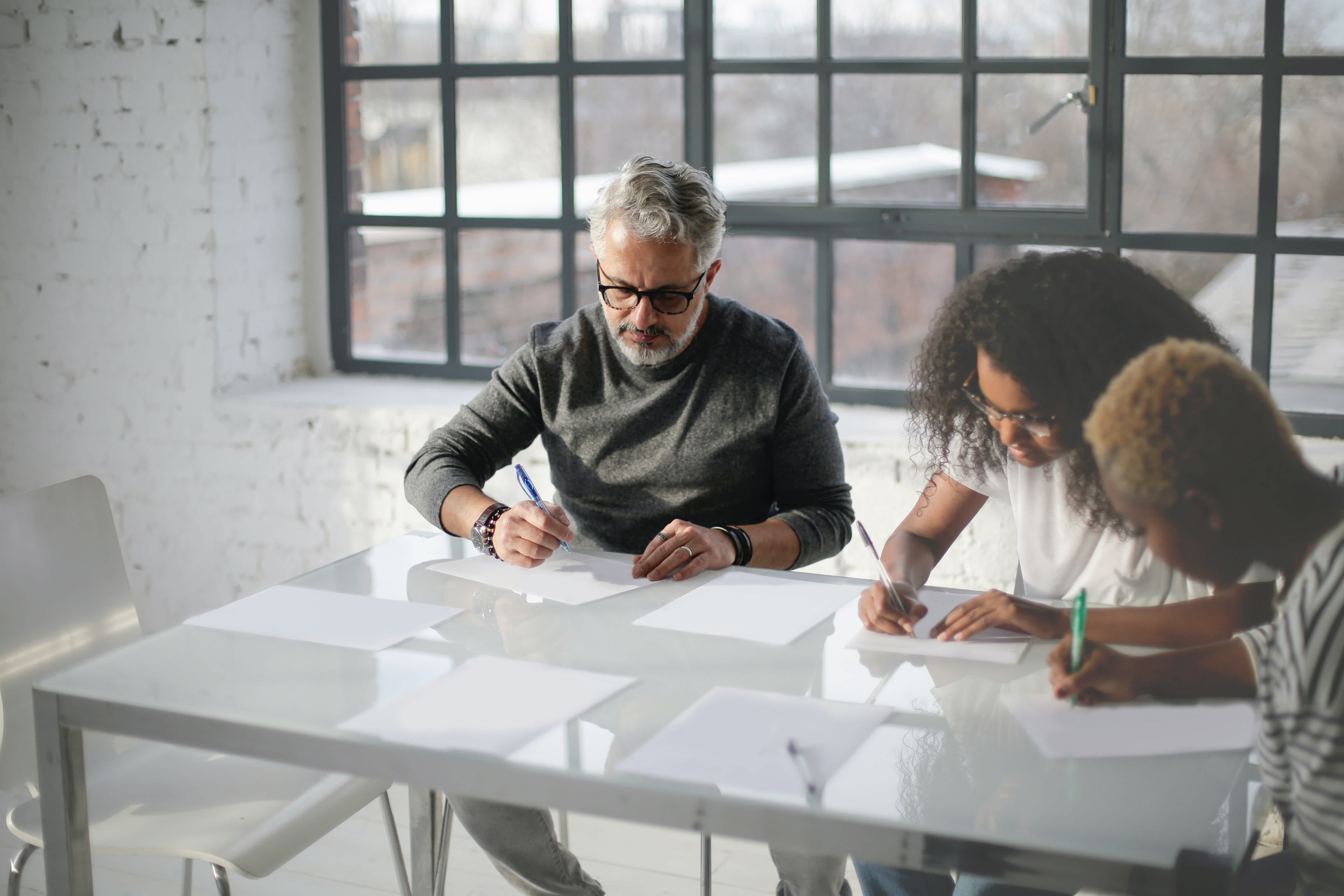 Three people writing something on paper