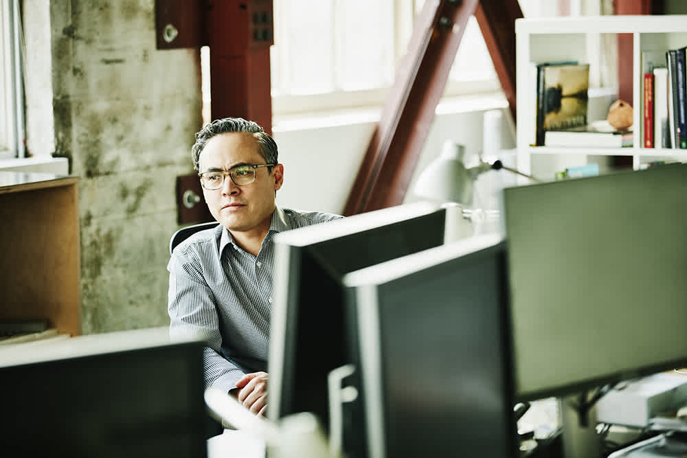 Man with glasses sitting behind desktop computers