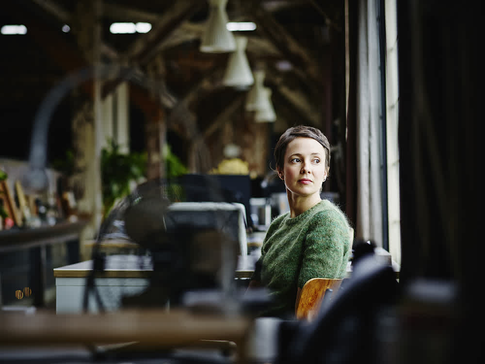 woman in green at office looking out window