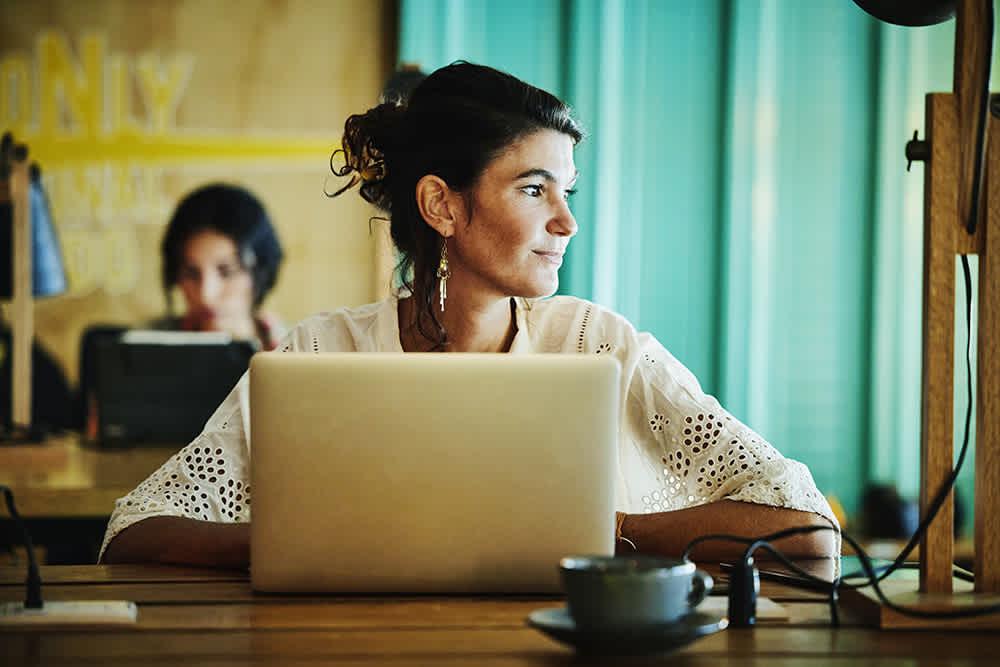 Woman in white sitting in front of laptop looking to the side