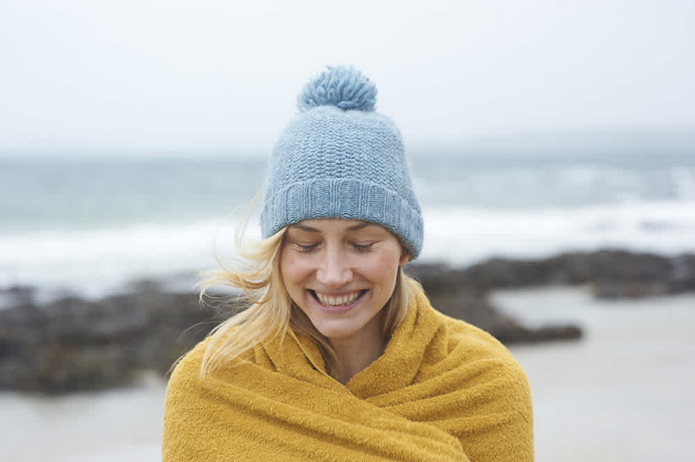 Woman outside smiling wrapped in yellow blanket