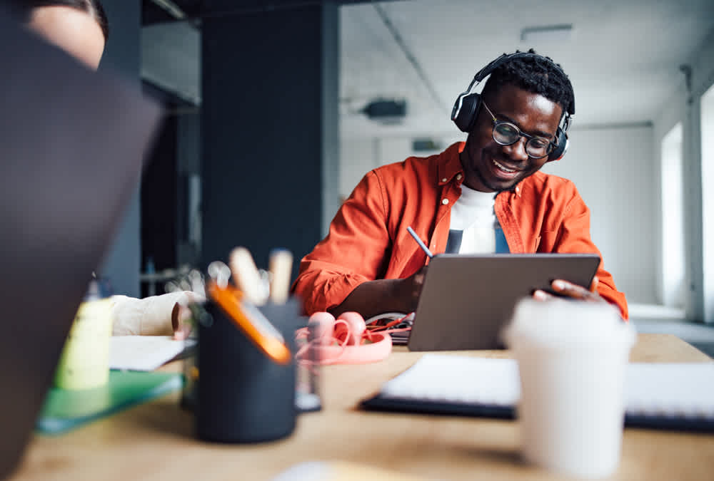 Black man in orange shirt working with headphones on 