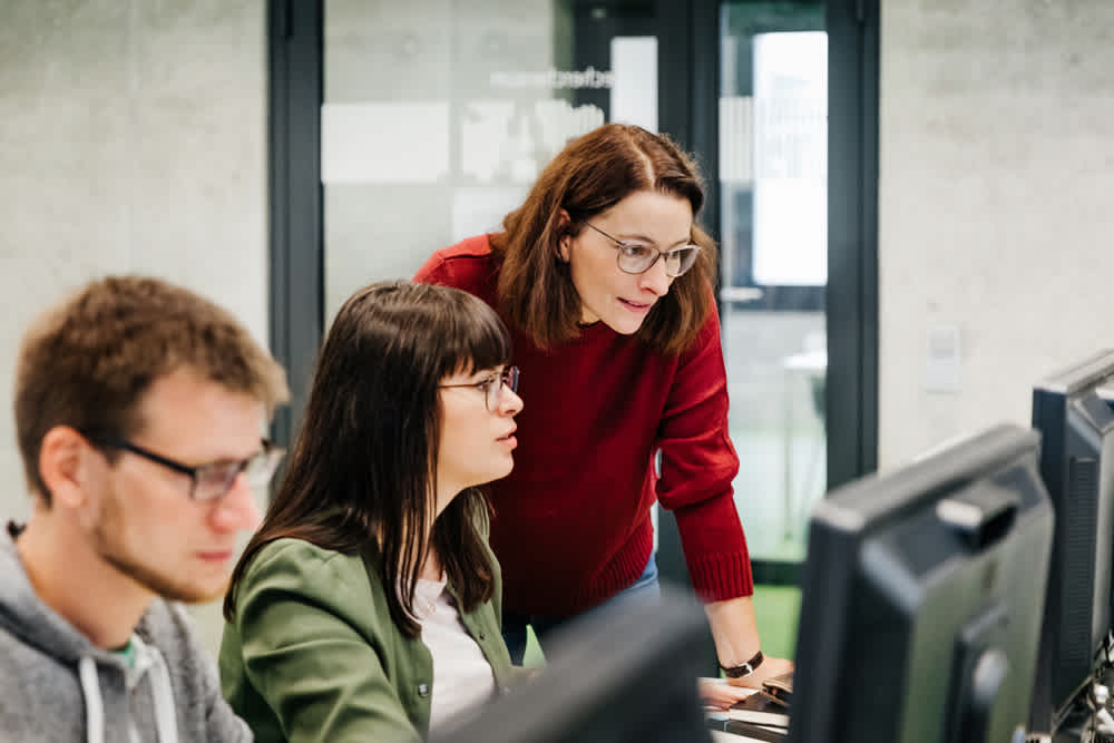 Employees around computer assisting each other
