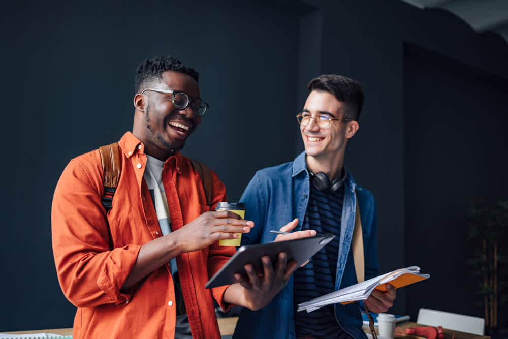 Black and white male coworkers in glasses talking and laughing