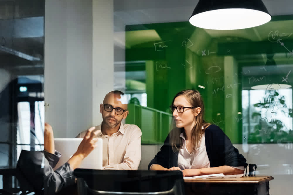 male and female colleagues listing to third teammate sitting in small coworking space