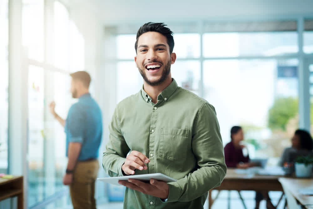 Man in green smiling holding tablet