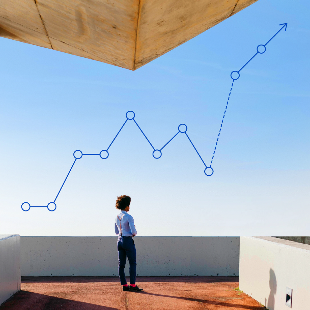 Person standing on a rooftop looking at a blue trend line chart against a clear sky