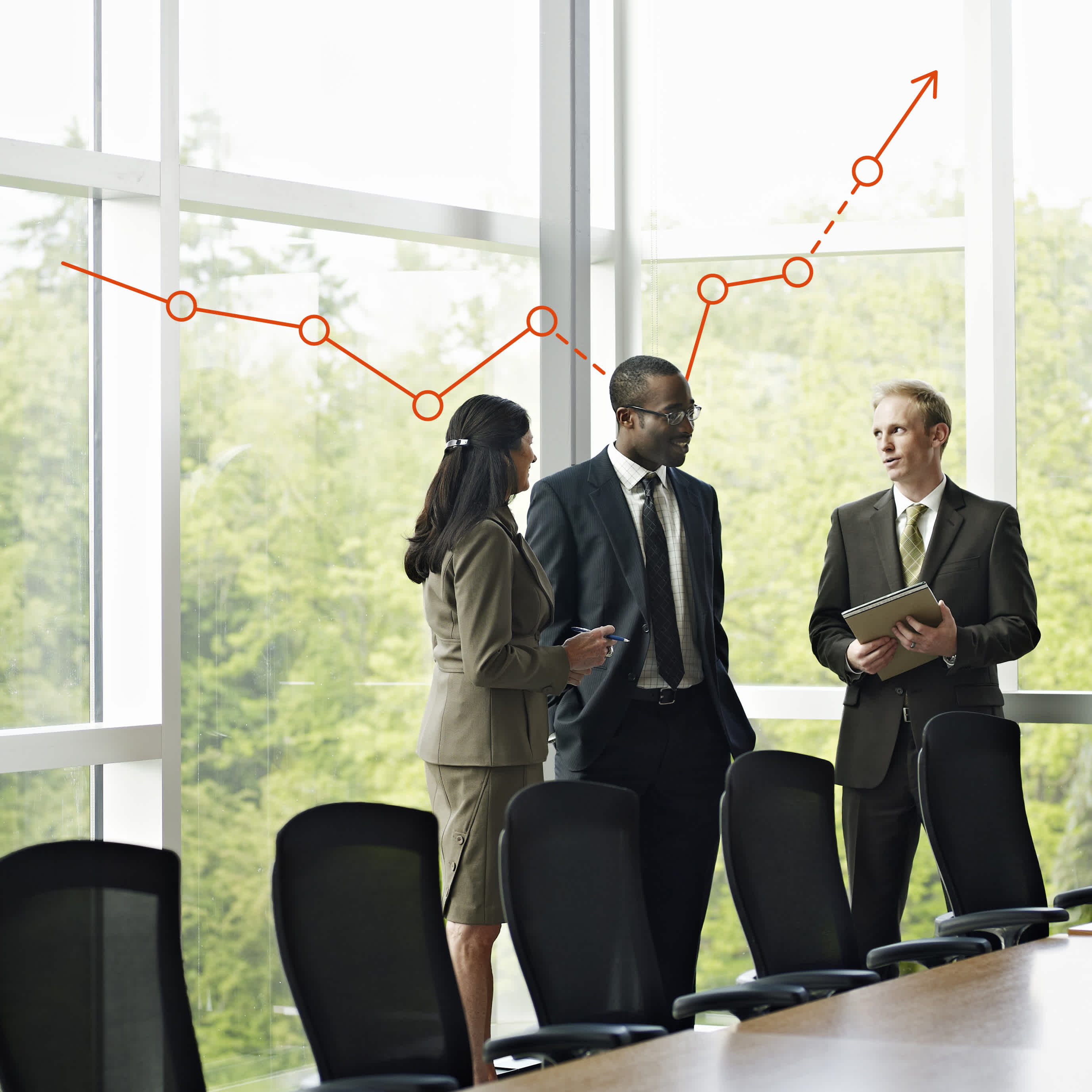 Three business professionals stand and talk in a modern conference room with large windows. Behind them, a red upward-trending line graph is drawn on the glass, symbolizing business growth or success.