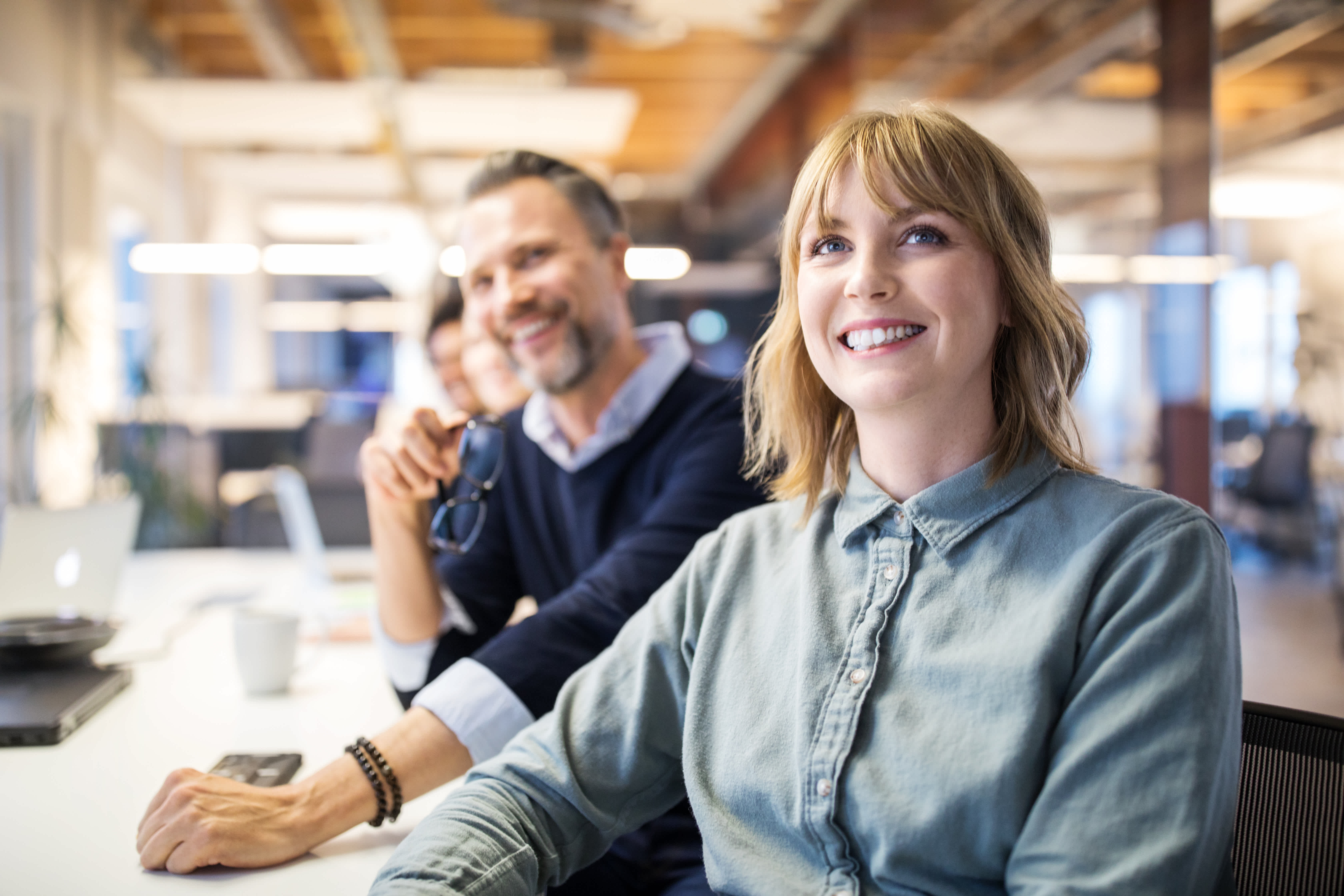 three young coworkers walking and laughing together in office hall