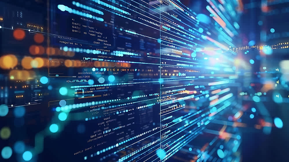 Computer code and data visualizations glow on multiple transparent screens in a dark, modern digital environment, with blue and orange light effects suggesting speed, connectivity, and advanced technology.
