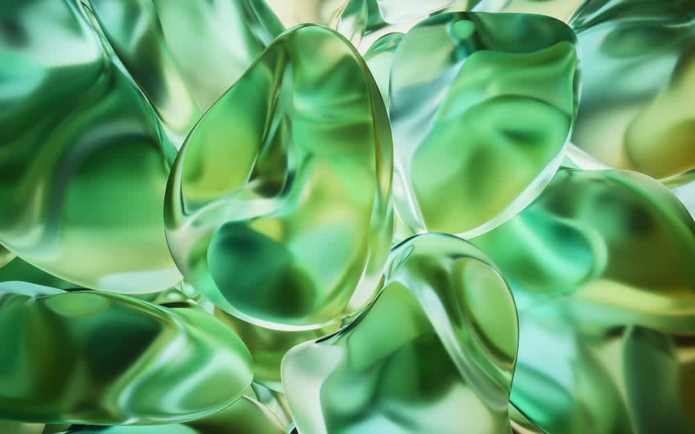 Abstract close-up image of shiny, translucent green and yellow shapes overlapping and reflecting light, creating a smooth, glossy, and organic appearance.