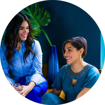 two women smiling, sitting together at office in blue
