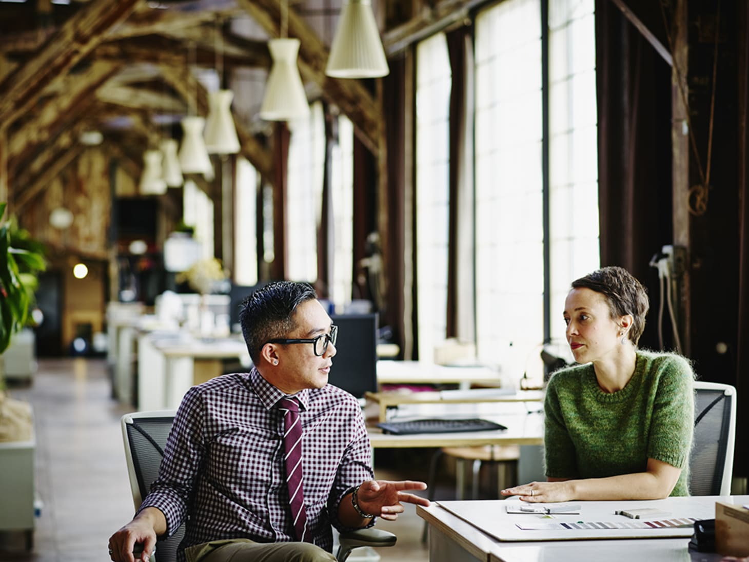 stylish man and woman chatting in a large office 