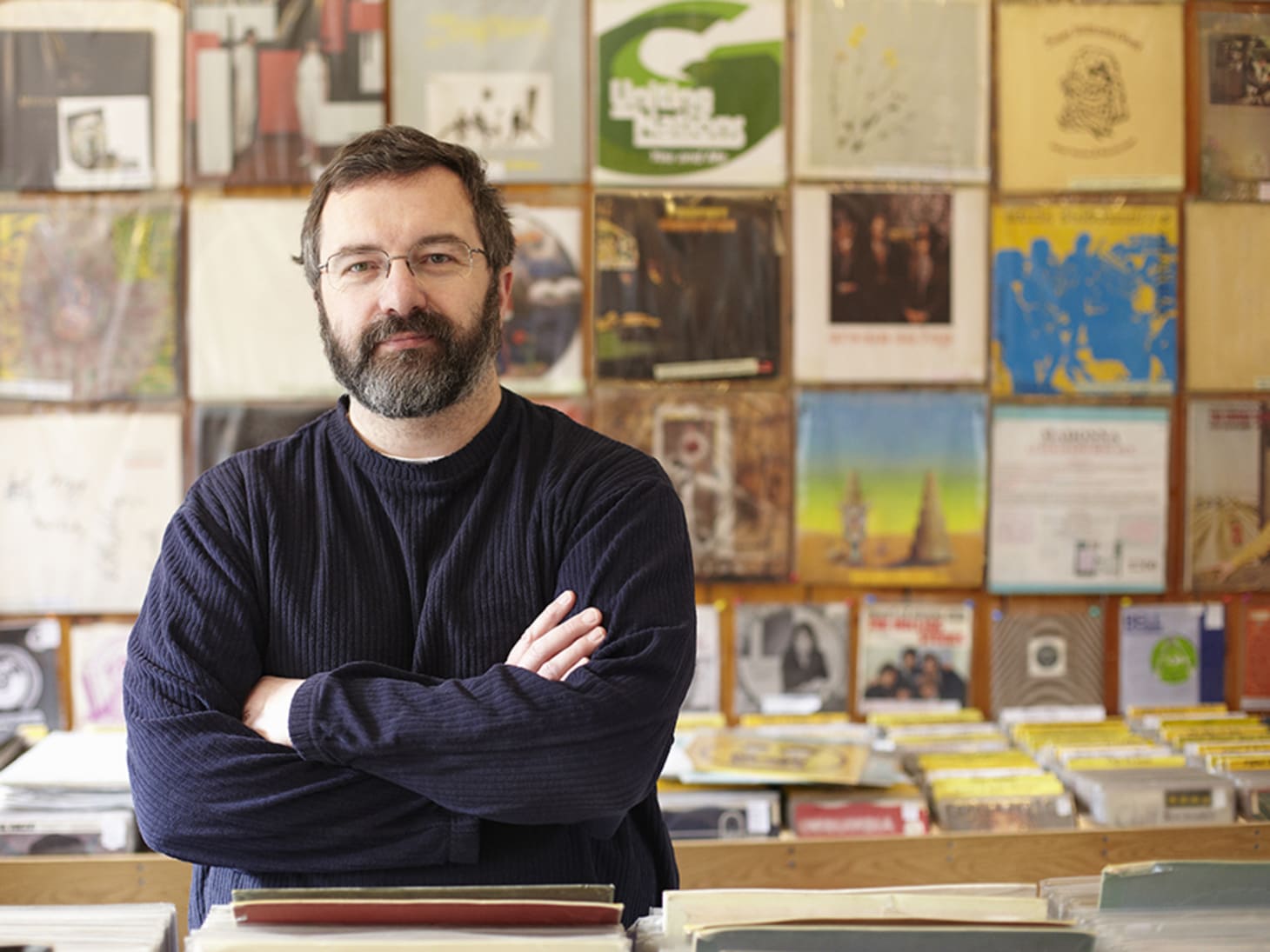 record shop owner in front of wall of records 