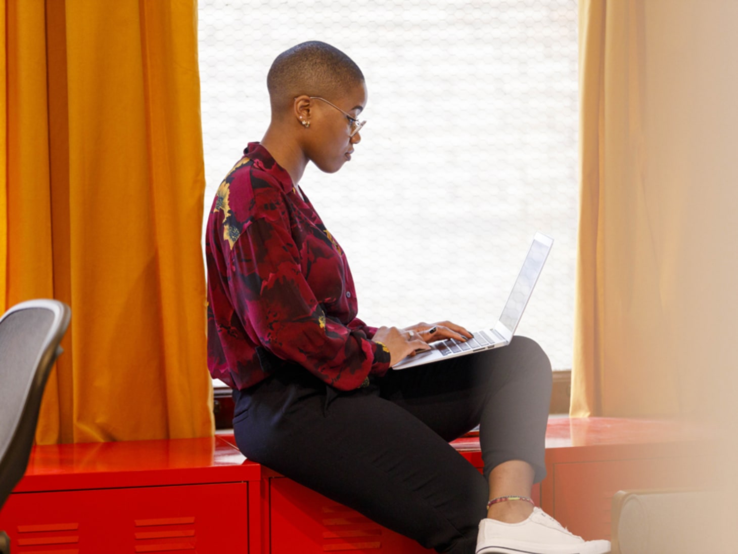 Black woman working at laptop in window sill