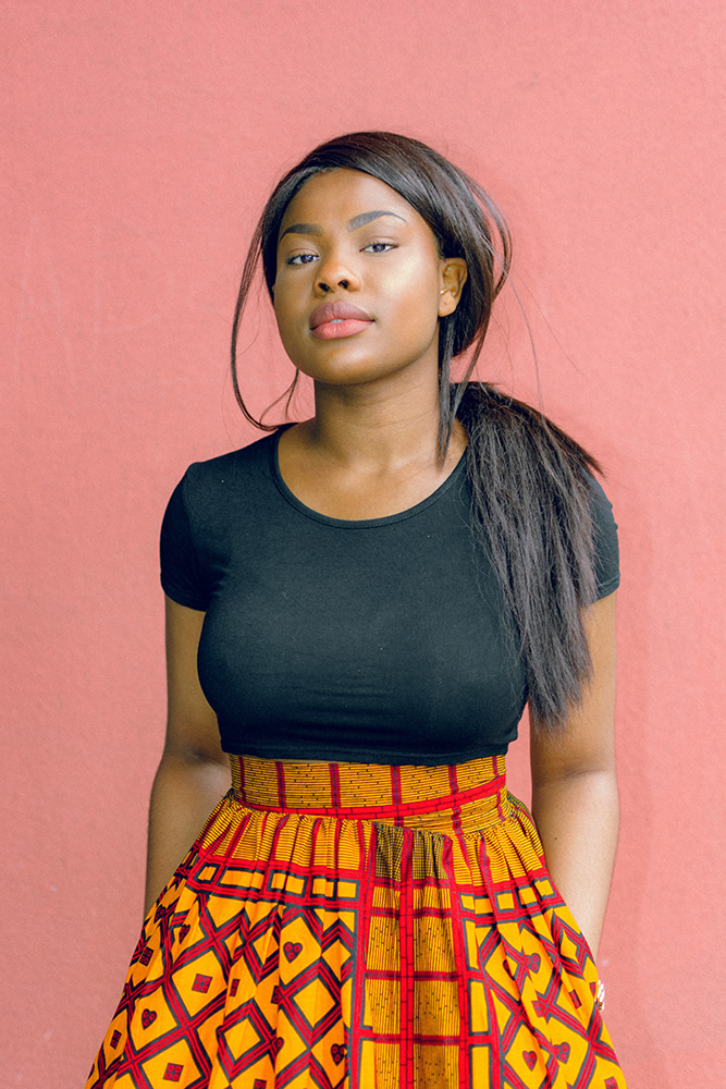 young Black woman in black top, looking at the camera with strength and confidence