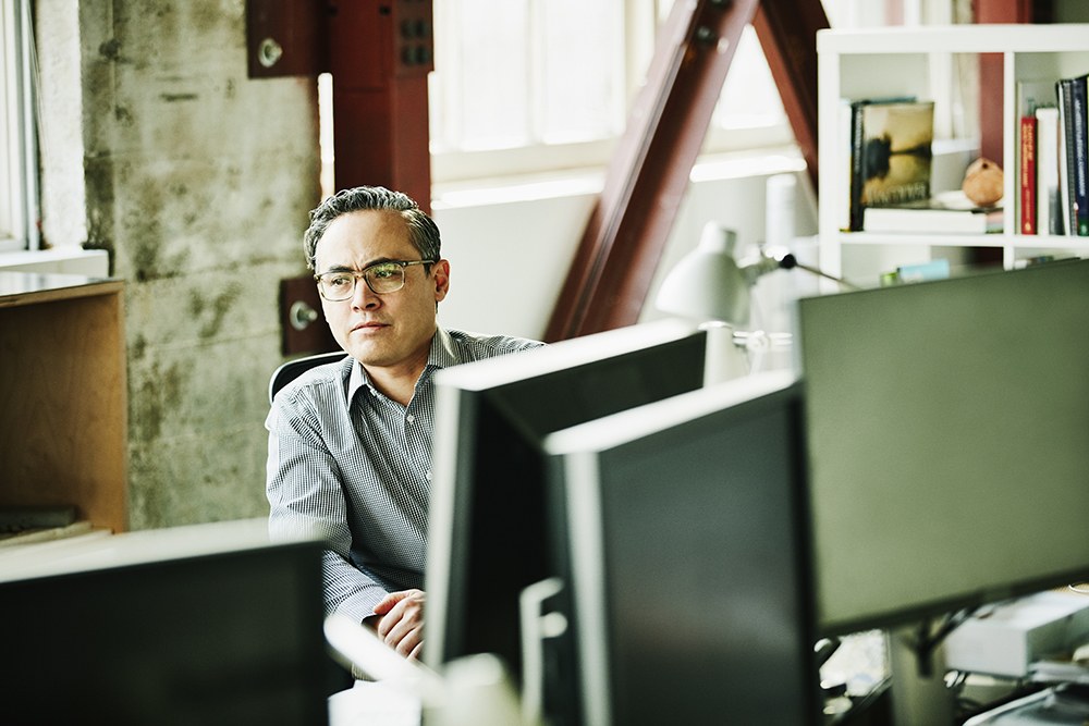 Man with glasses sitting behind desktop computers