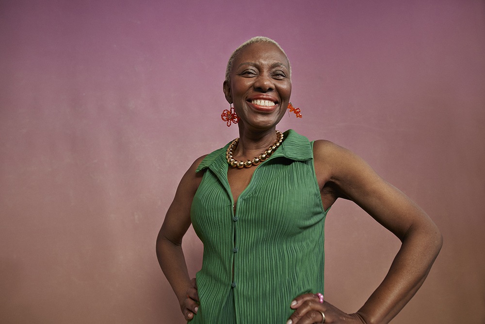 Black woman in green top, smiling big and bright