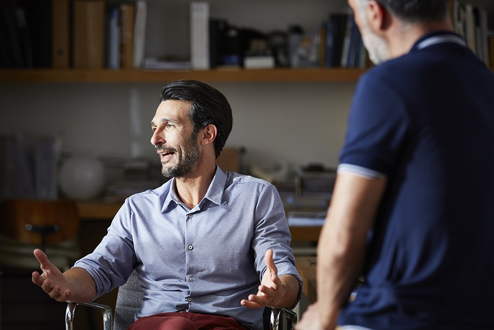 white man in chair at office, talking