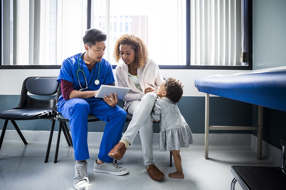 male nurse assisting mother and young child in hospital room