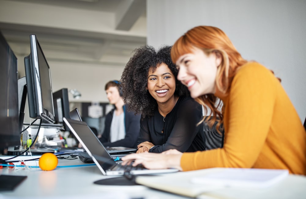 Women in office smiling looking at laptop