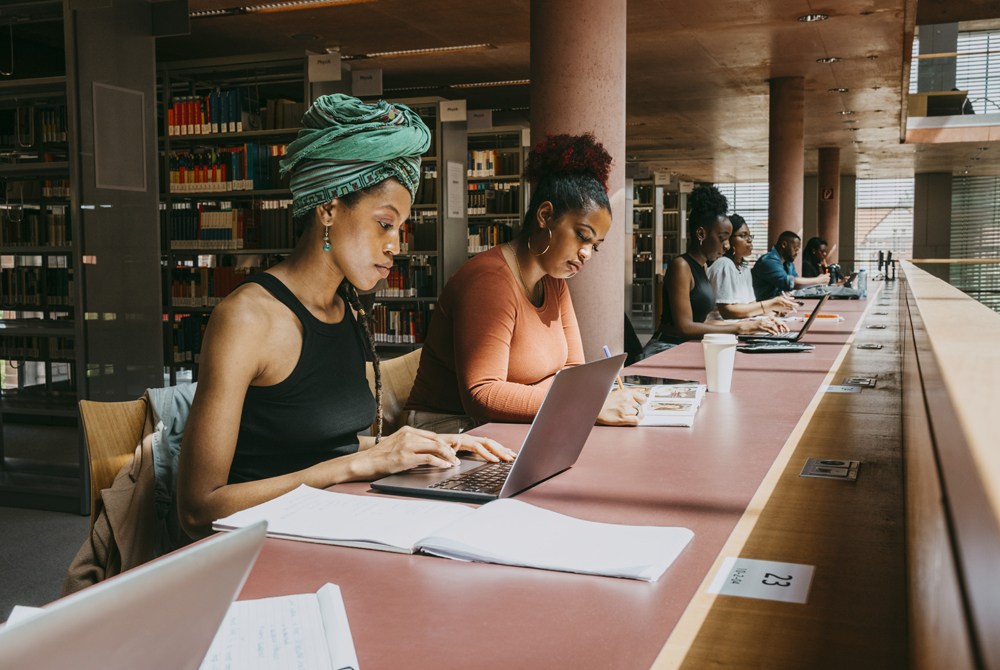 A group of people sitting at a table with laptops