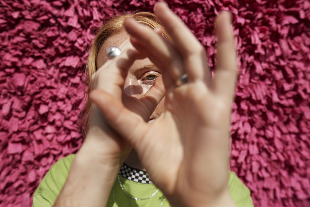 red-haired white woman looking through her hands like a kaleidoscope