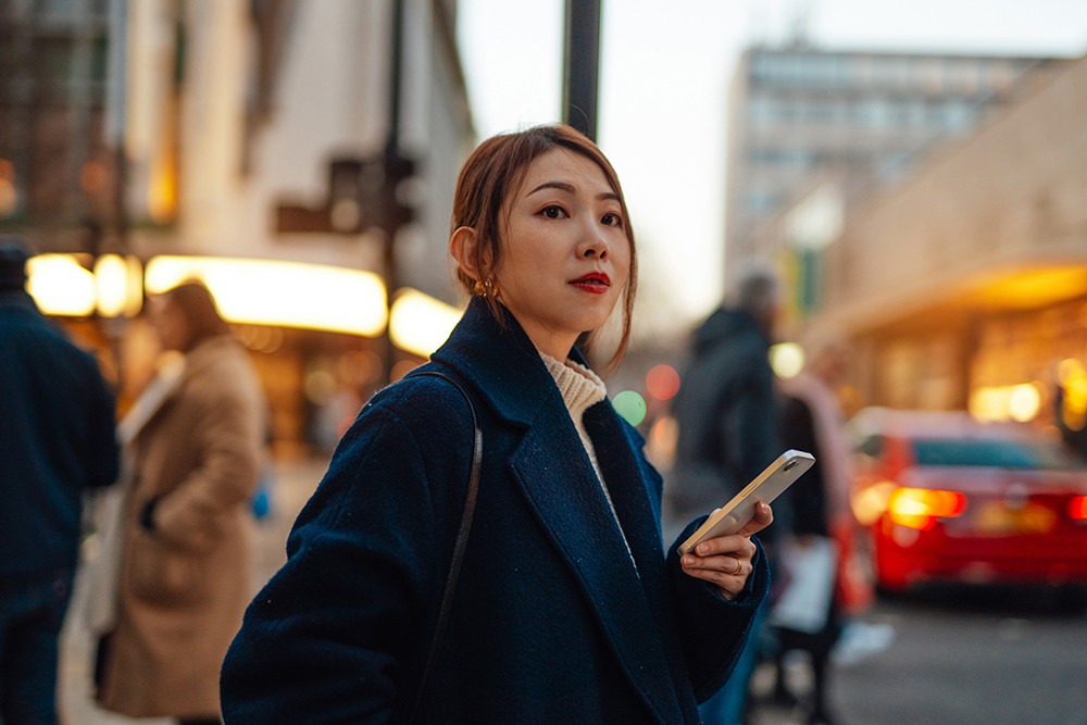 Asian woman in navy jacket waiting for a taxi