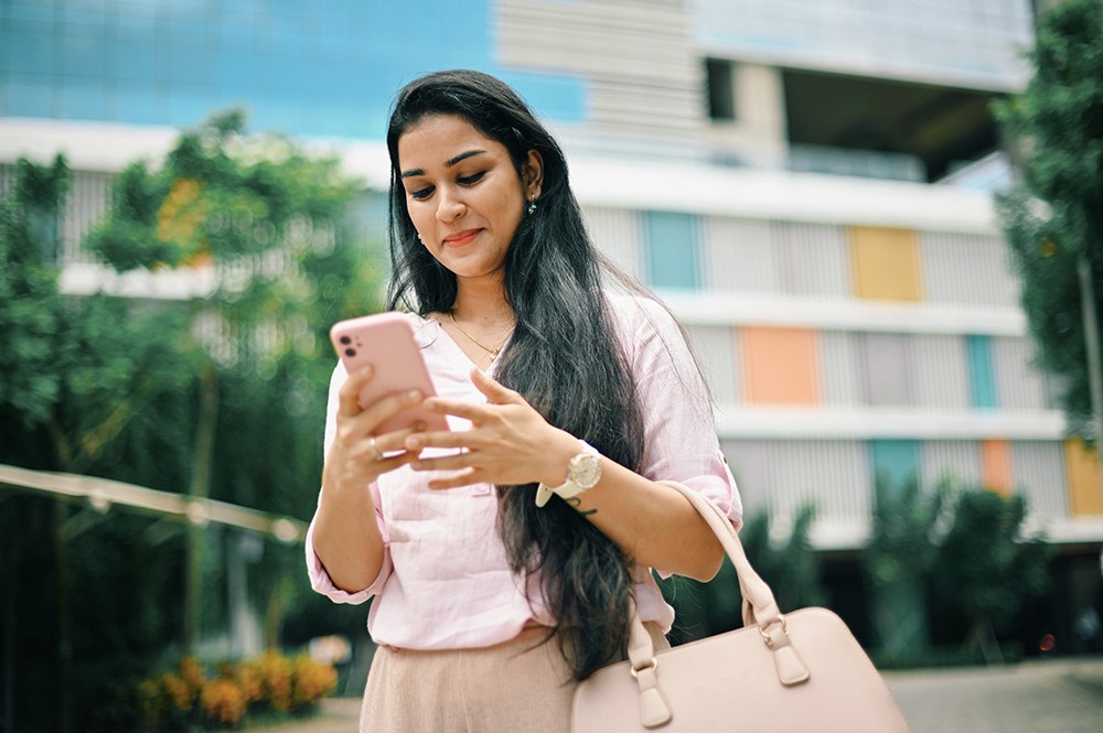 Indian woman in pink texting on her cell phone