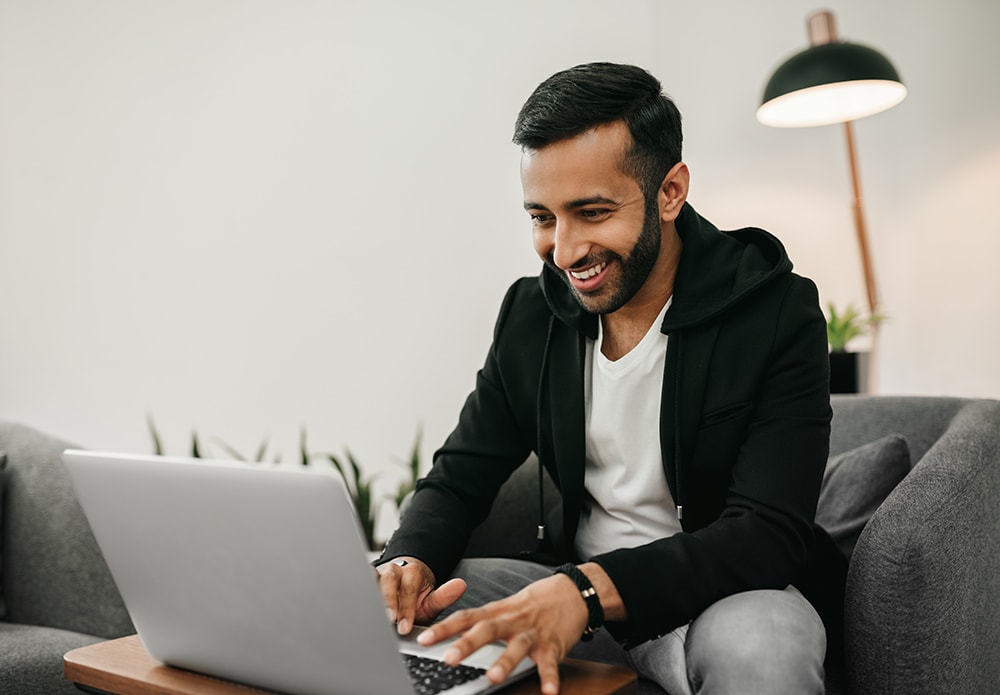 Indian man working on laptop in comfy chair