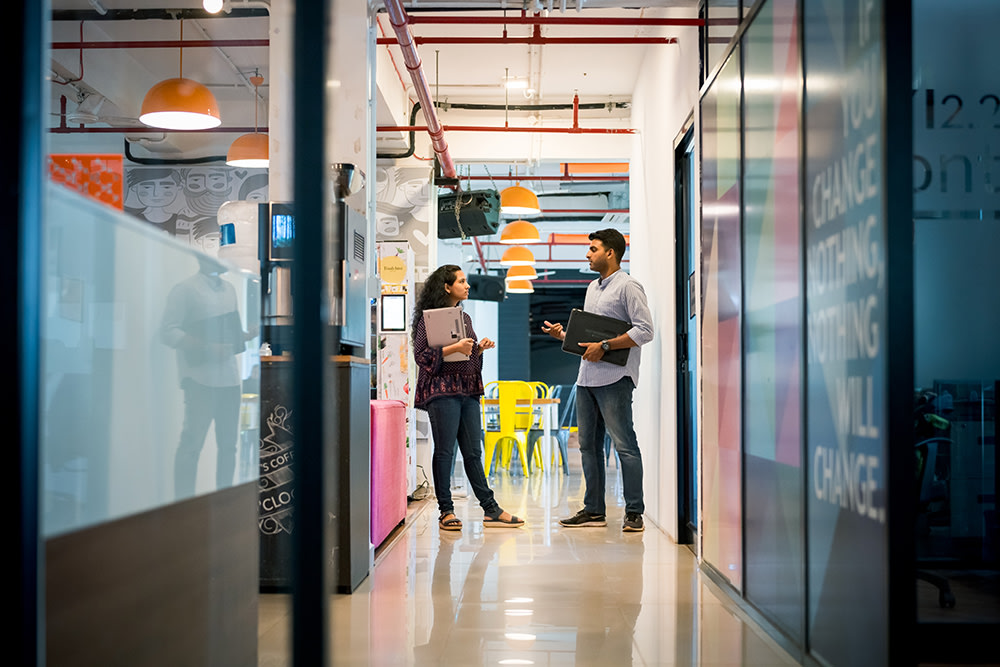 female and male Indian colleagues talking in office hall