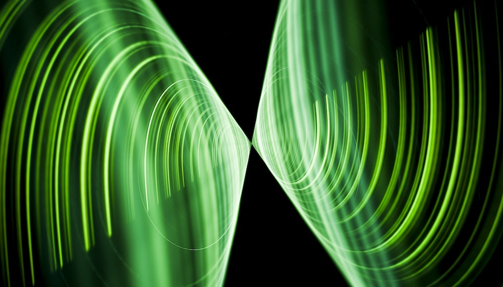 Abstract image of intersecting green, glowing, curved lines and concentric circles on a black background, creating a symmetrical and futuristic pattern.