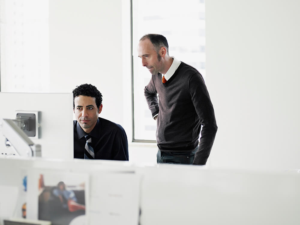 Two men working together in an office looking at computer