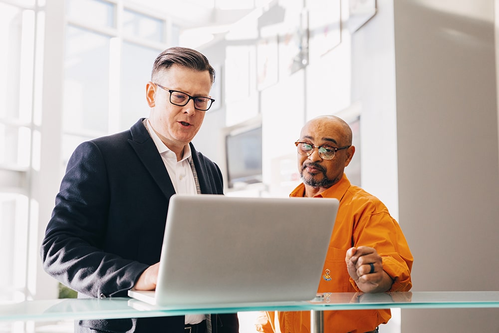 two men in glasses working at a laptop 