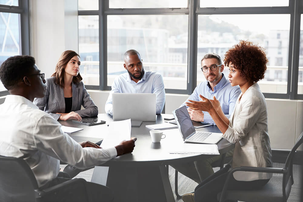 A group of employees discussing work around a table