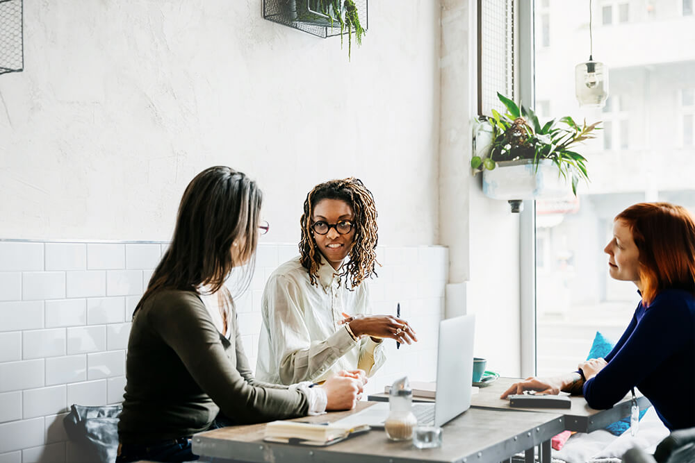 three female coworkers meeting at a cafe