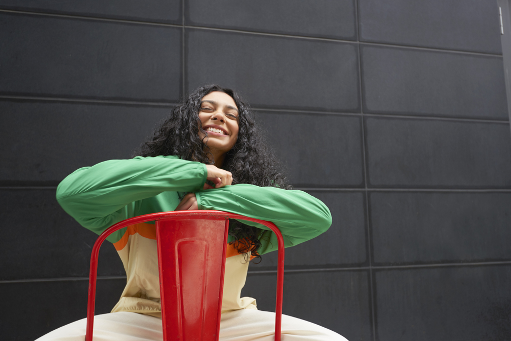 woman with curly black hair sitting backwards on red chair