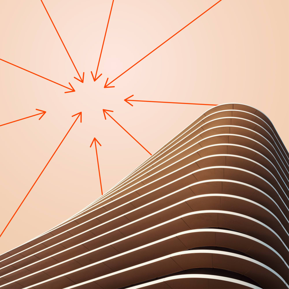A modern, curved building with layered horizontal lines set against a peach sky. Red arrows radiate inward from various directions, converging at a central point above the structure.